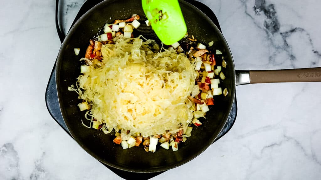 Mixing the sauerkraut into the sauteed mixture.