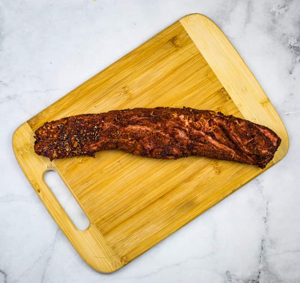 Spicy Pork Tenderloin resting on a wooden cutting board.