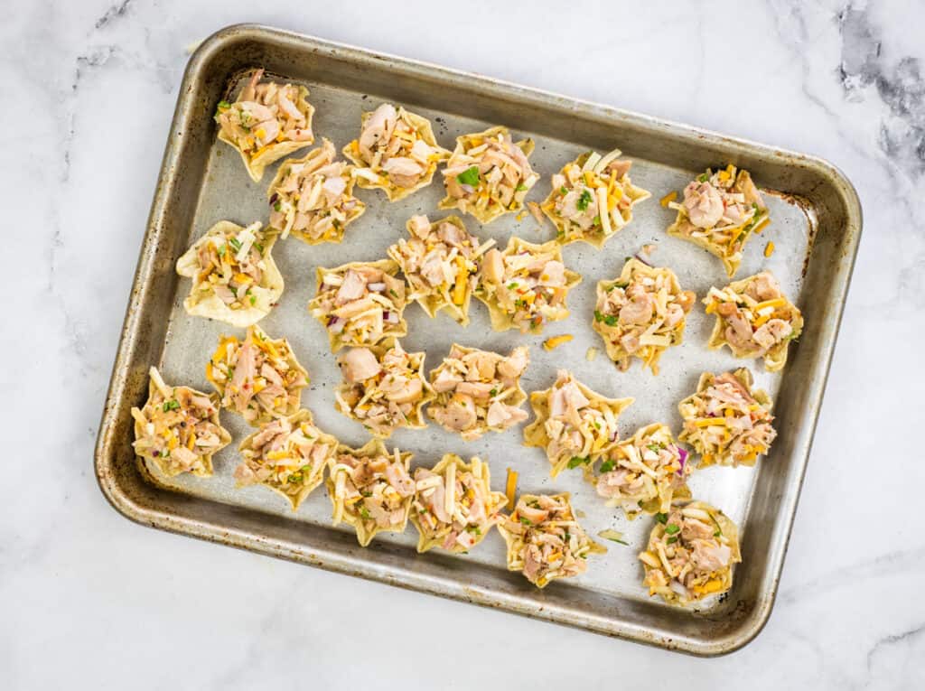 Filled tortilla chip scoops on a sheet pan.
