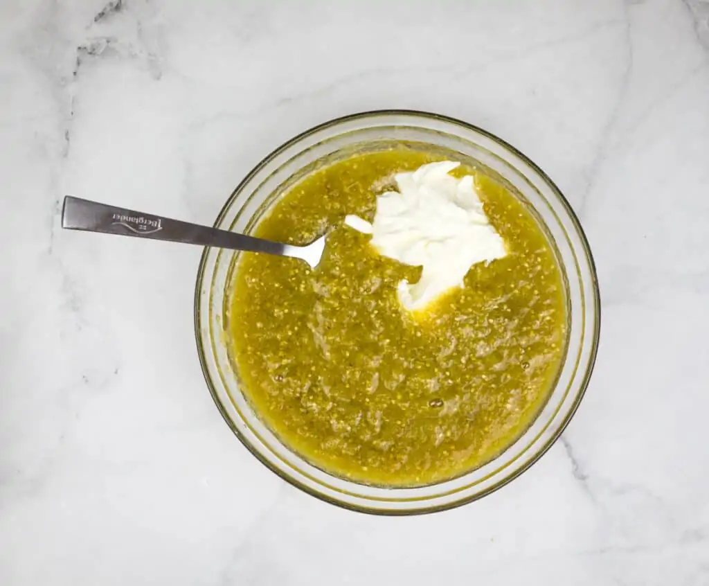 Mixing sour cream into a bowl of sauce for smoked chicken enchiladas.