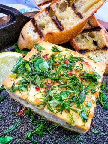 closeup of grilled feta with grilled bread in the background