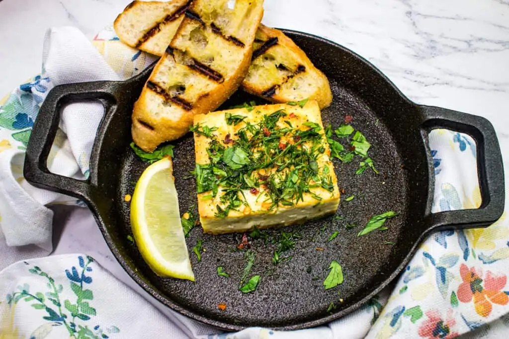 grilled feta with grilled bread in a round cast iron dish