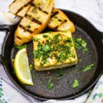 grilled feta with grilled bread in a round cast iron dish