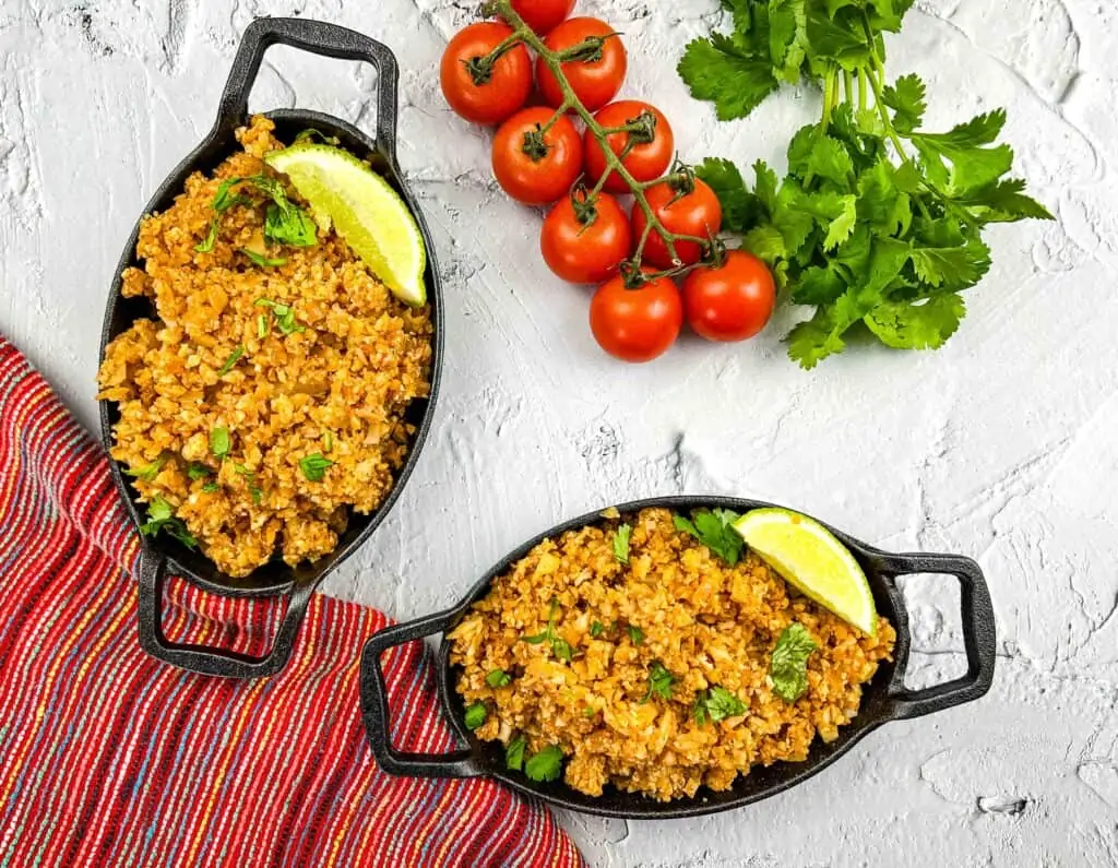 Vegan Mexican Cauliflower rice in two black oval serving dishes