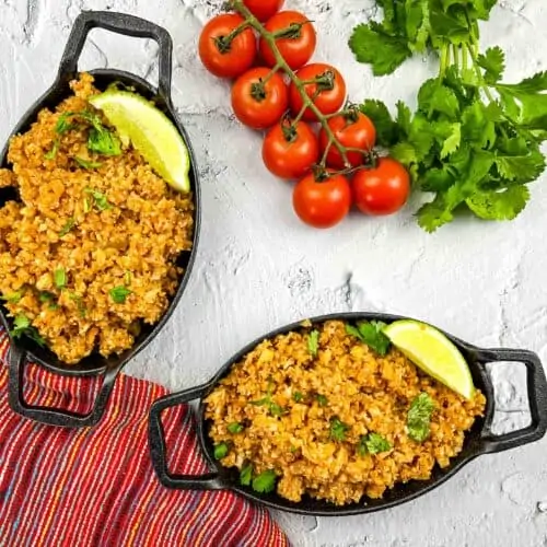 Vegan Mexican cauliflower rice in two black oval serving dishes