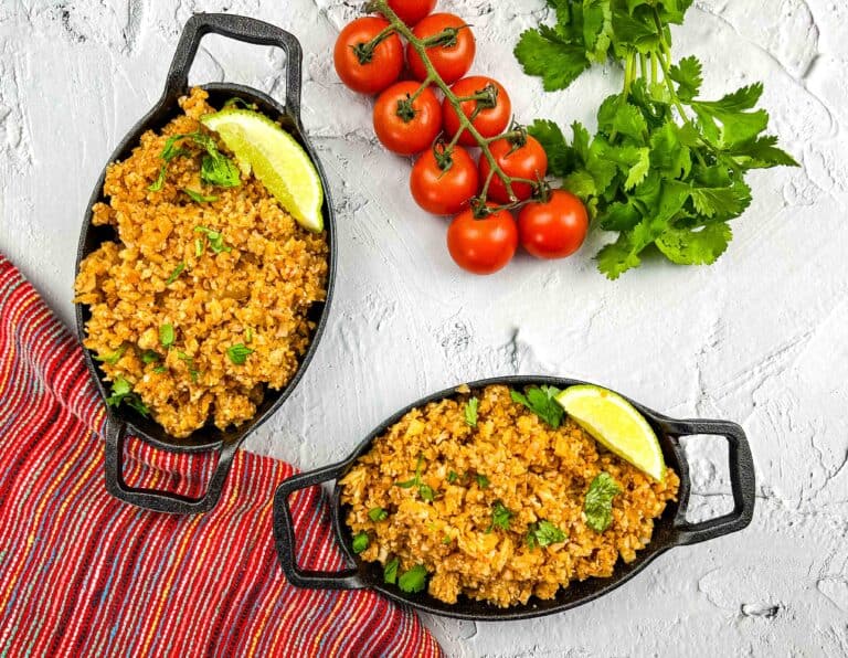Vegan Mexican cauliflower rice in two black oval serving dishes