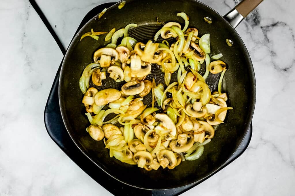 onions and mushrooms in a skillet to make leftover roast beef stroganoff