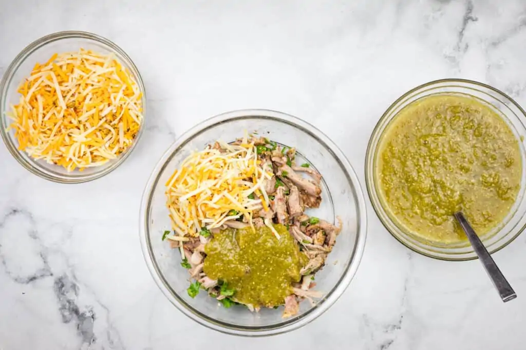 A bowl of chopped chicken, sauce and cheese.
