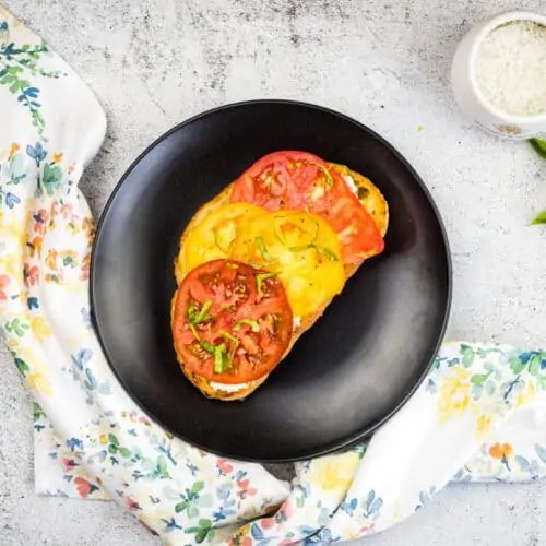grilled bread with tomato and ricotta on a black plate