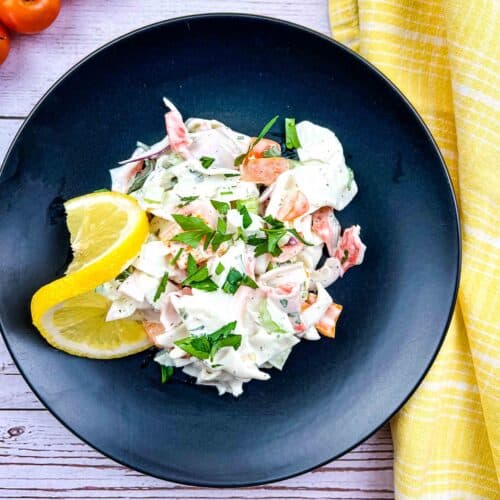Deli seafood salad on a black plate.