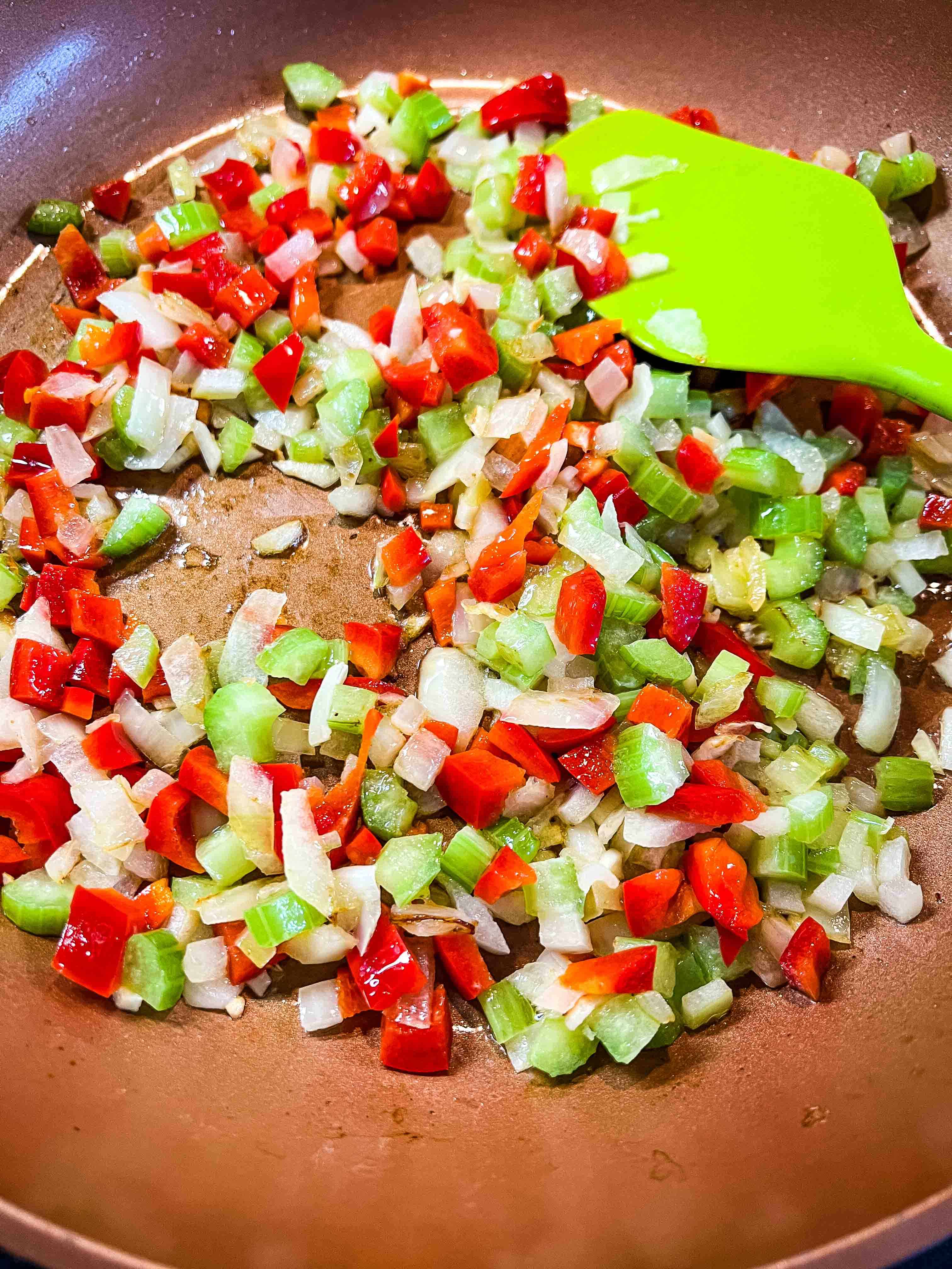 Onion, celery, bell pepper sauteeing in a skillet.