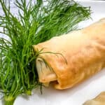 spanakopita roll on a plate with dill.