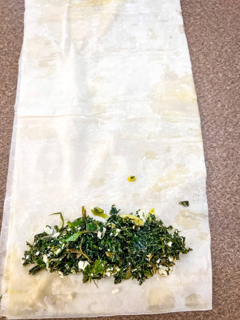 filling and rolling the phyllo sheets to make spanakopita rolls