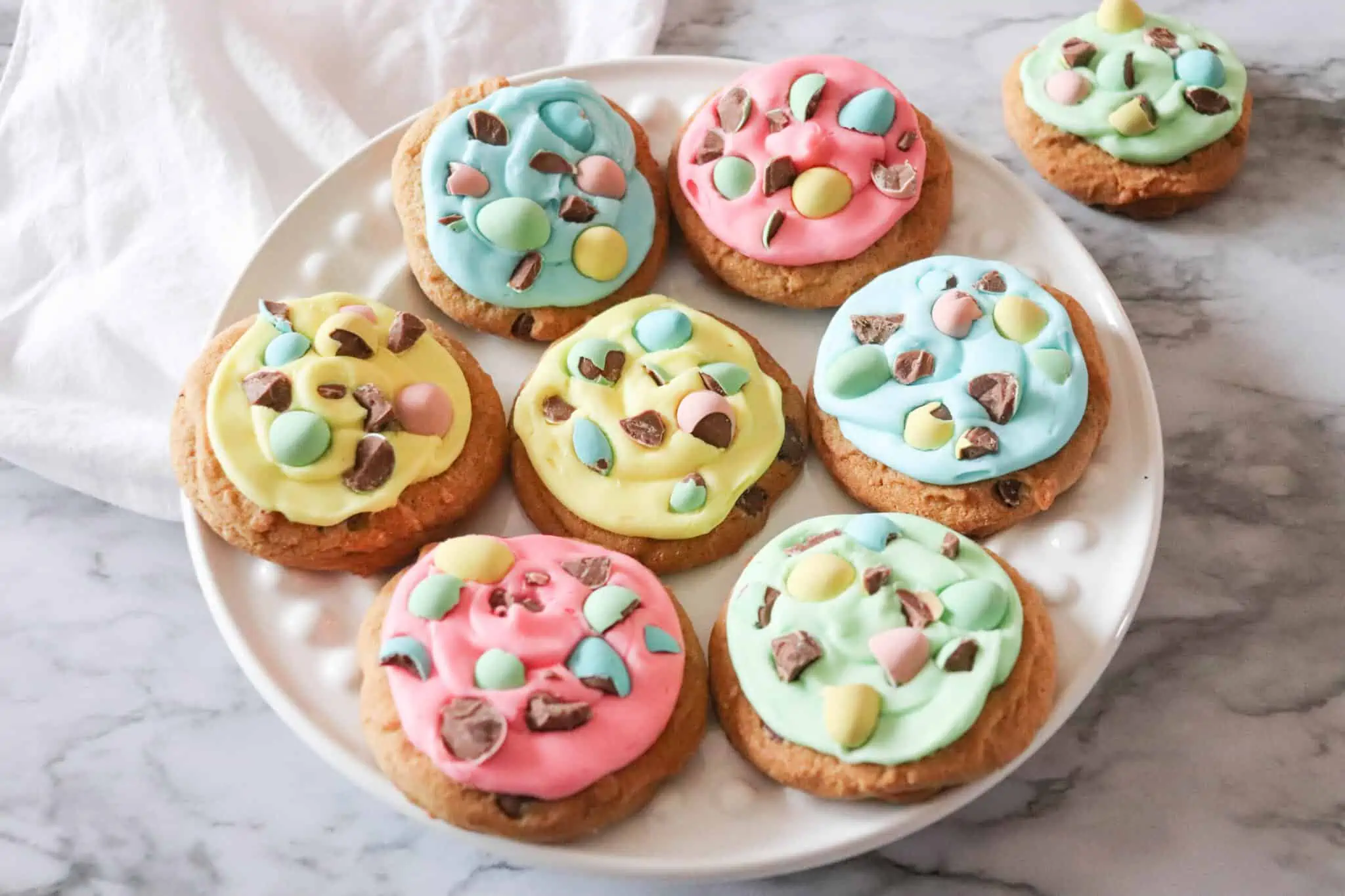Mini egg cookies on a white plate with colorful icing.