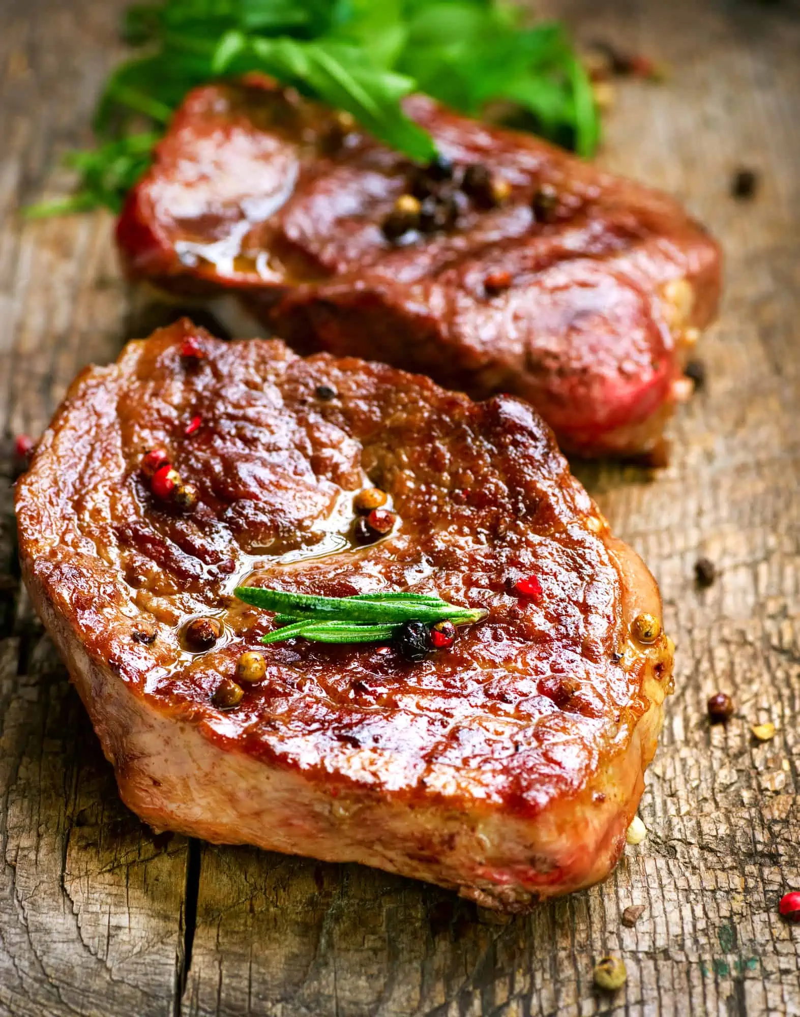 2 grilled steaks on a cutting board