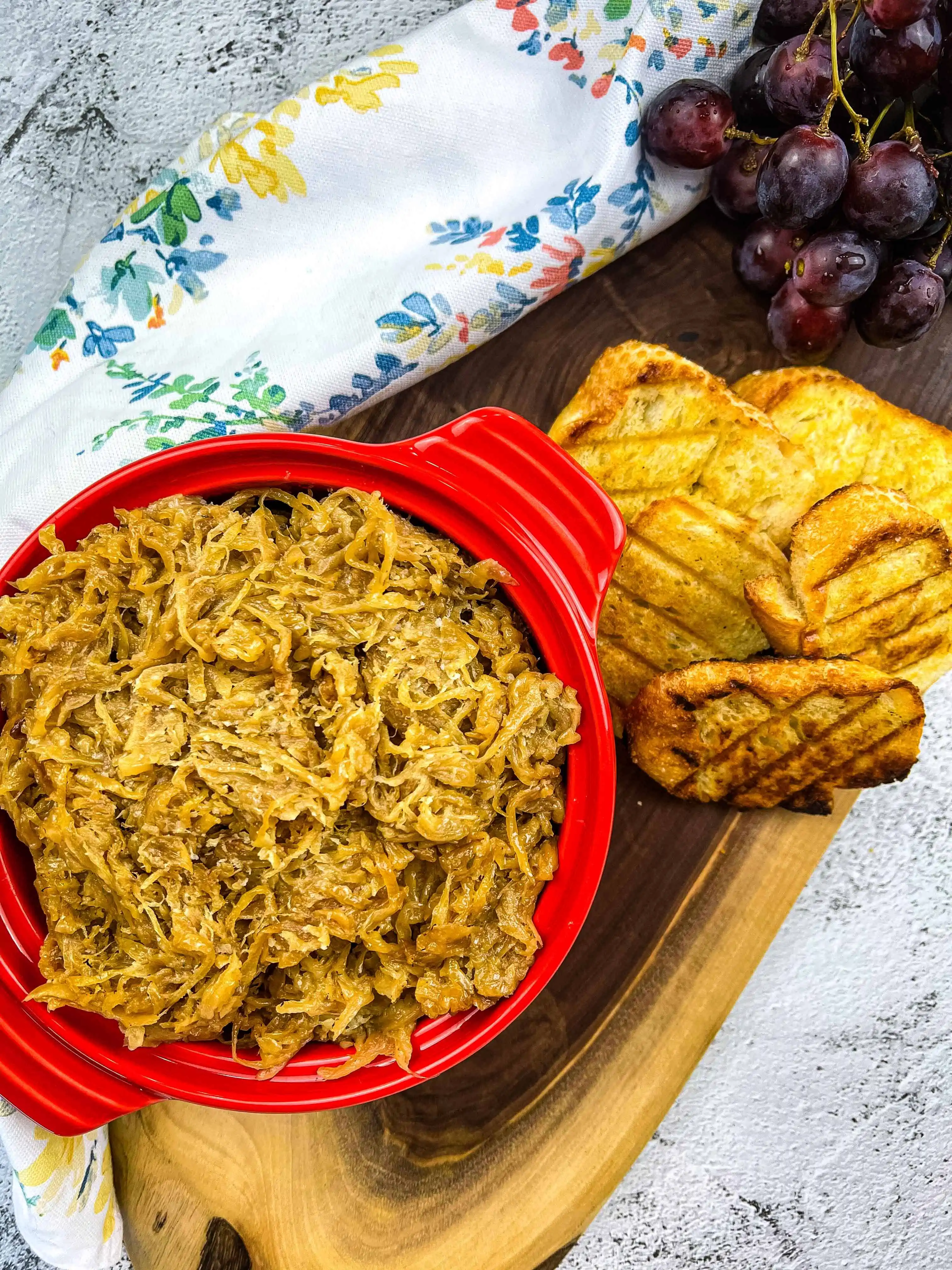 caramelized onions on a platter with toasted bread and grapes