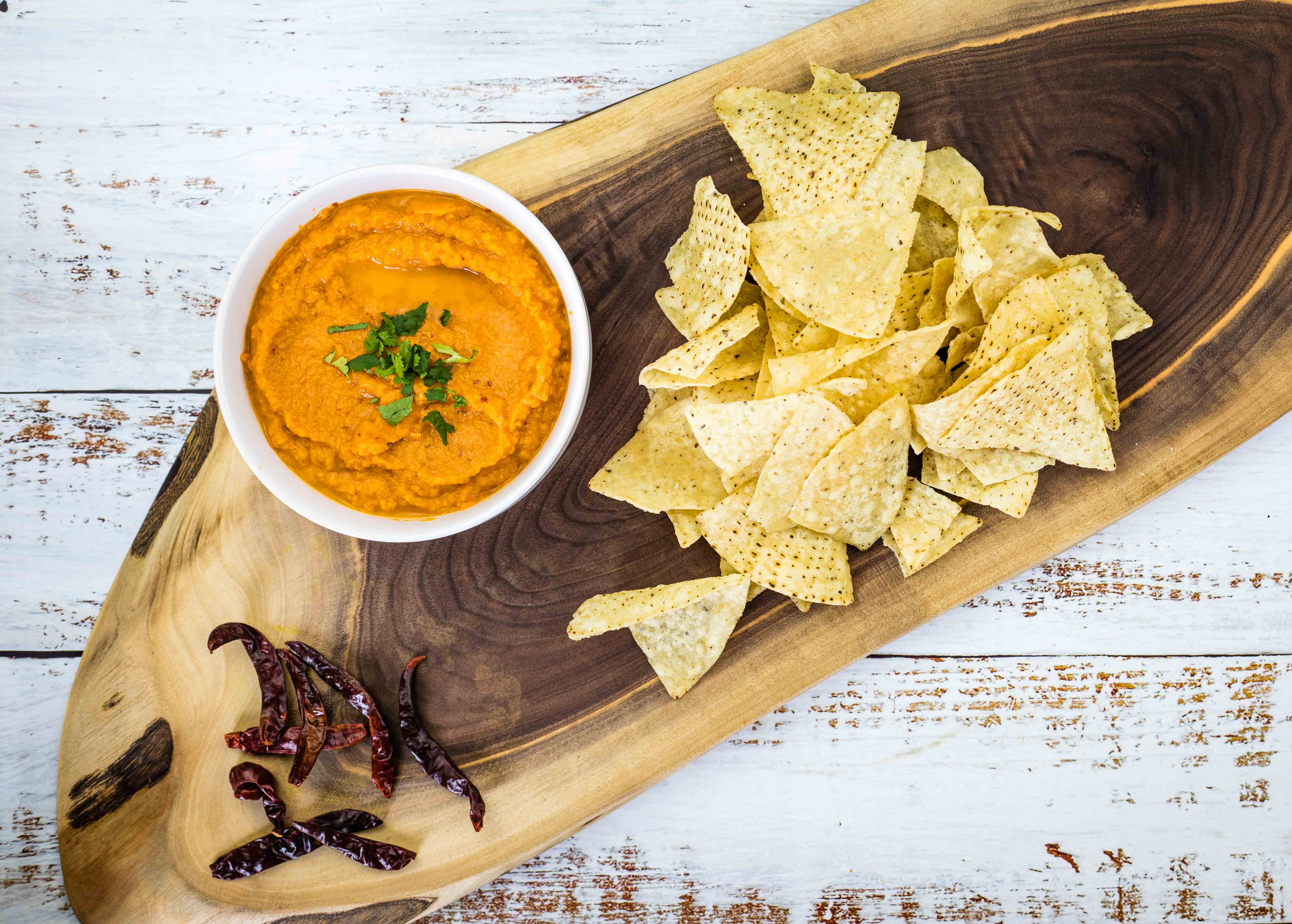 Chile de Arbol Salsa on wooden board with chips and chilies nearby.