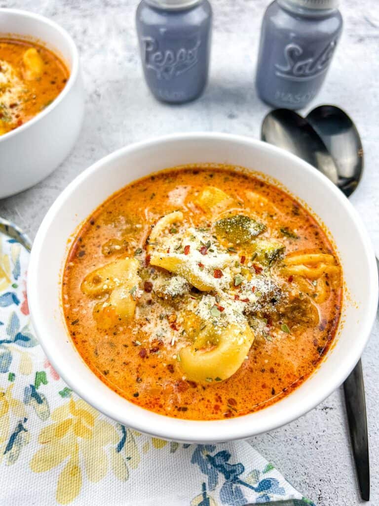 creamy instant pot tortellini soup with sausage in a bowl with spoons