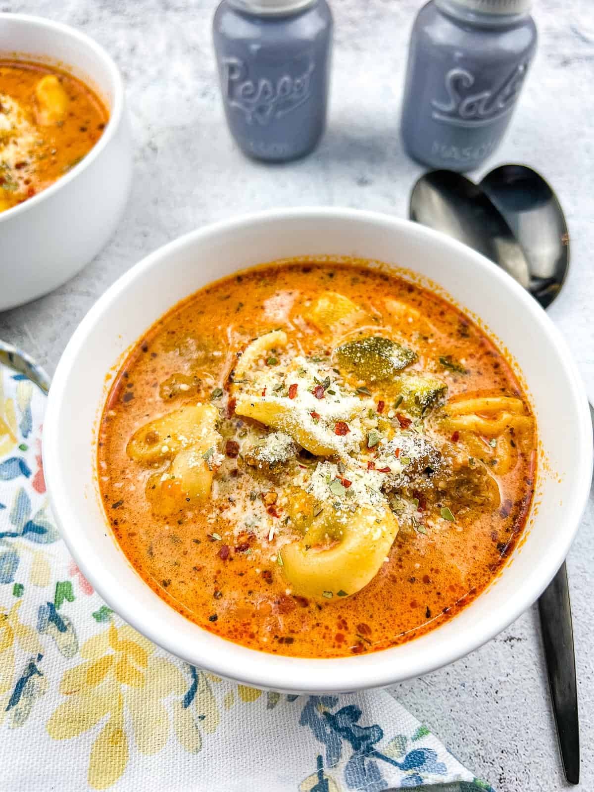 creamy instant pot tortellini soup with sausage in a bowl with spoons