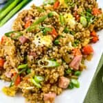 Ham fried rice garnished with green onions on a white platter.