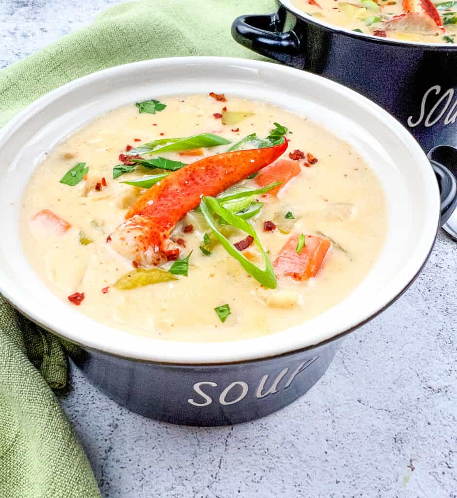 Lobster chowder in a black soup bowl.