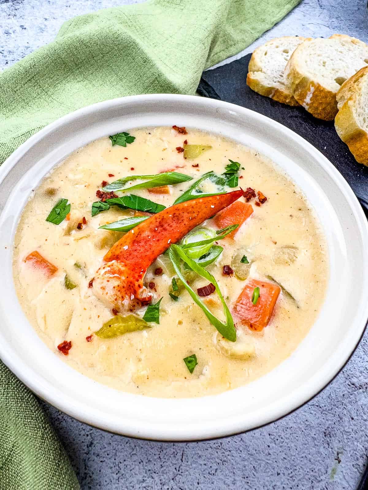 lobster chowder in a bowl with bread in background