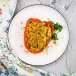 Seafood-stuffed red peppers on a white plate.