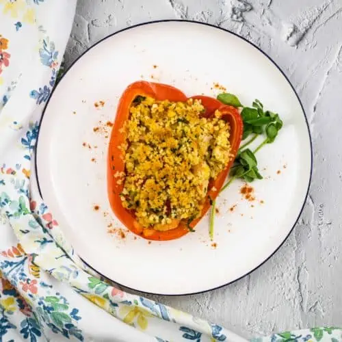 Seafood-stuffed red peppers on a white plate.