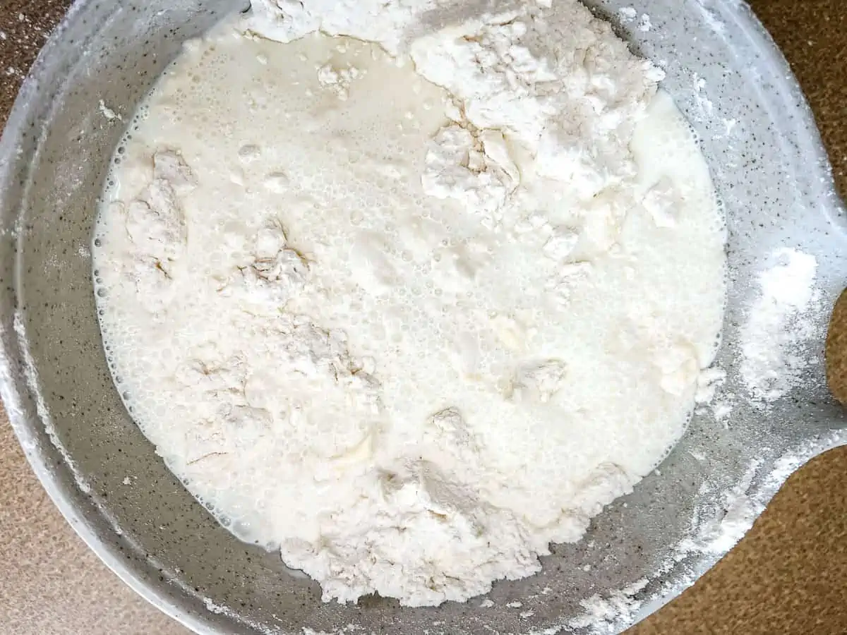 Milk and sour cream mixture added to the flour and butter in a bowl.