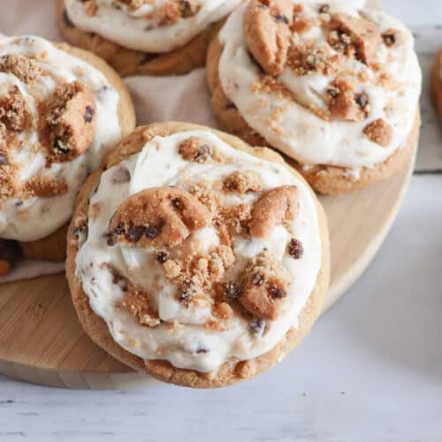 Cookie frosted chocolate chip cookies on a wooden board.