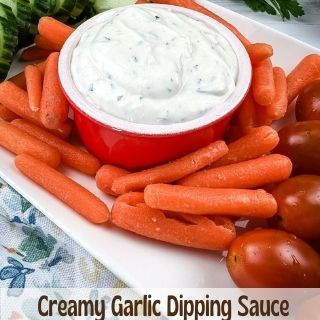 creamy garlic dipping sauce in a bowl with veggies on the side