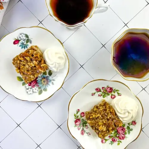 maple pecan pie bars on saucers with coffee in the background