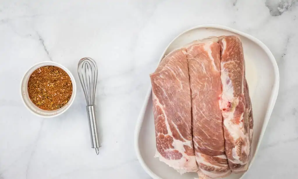 the carnitas pork rub in a bowl next to the raw pork