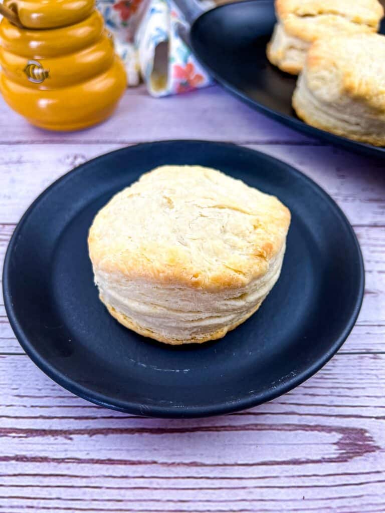 flaky smoked biscuits on a plate with more biscuits in the background
