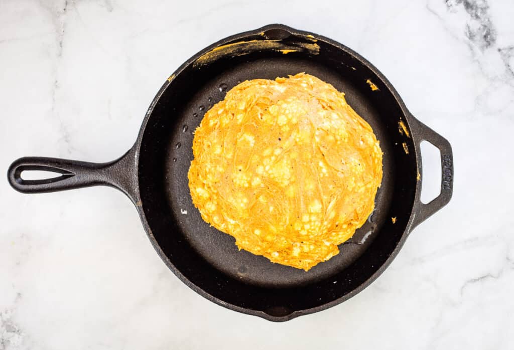 raw cauliflower in a cast iron pan coated with the butter-spice mixture.