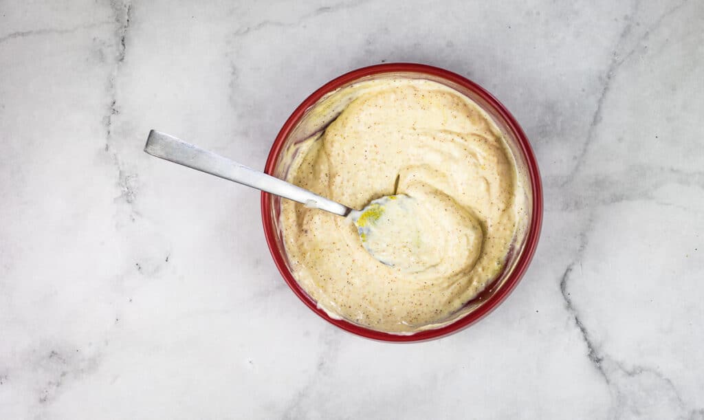 A bowl of spicy hummus with a spoon in it.