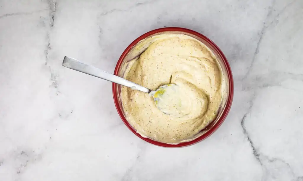 A bowl of spicy hummus with a spoon in it.