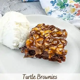 Turtle Brownie square on a plate with ice cream.