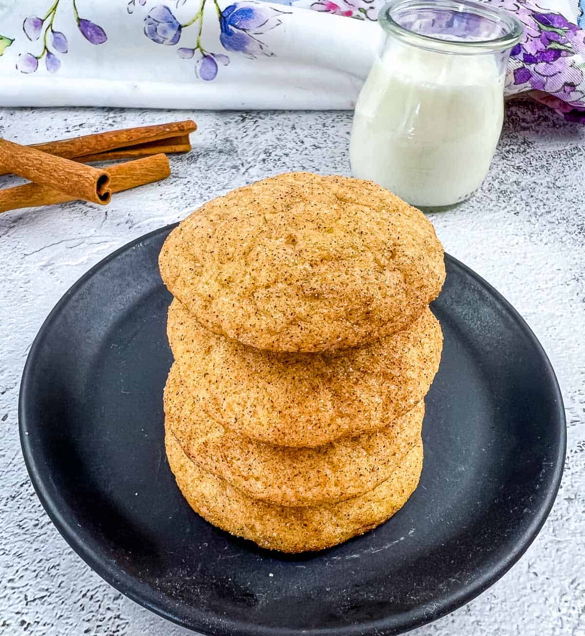 pumpkin snickerdoodles stacked on a plate next to milk