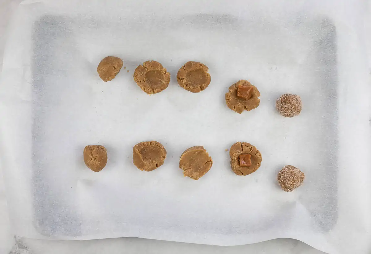 dough balls, indented dough balls, caramel-filled dough balls, and rolled cookie dough on a baking sheet