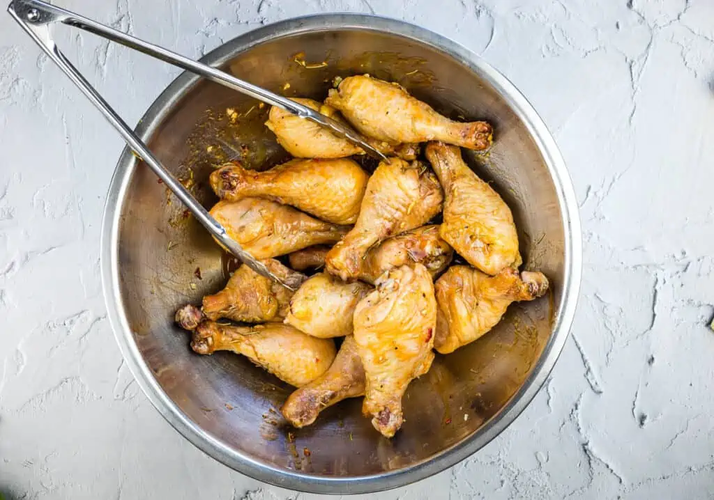 tossing chicken legs with the glaze in a large bowl