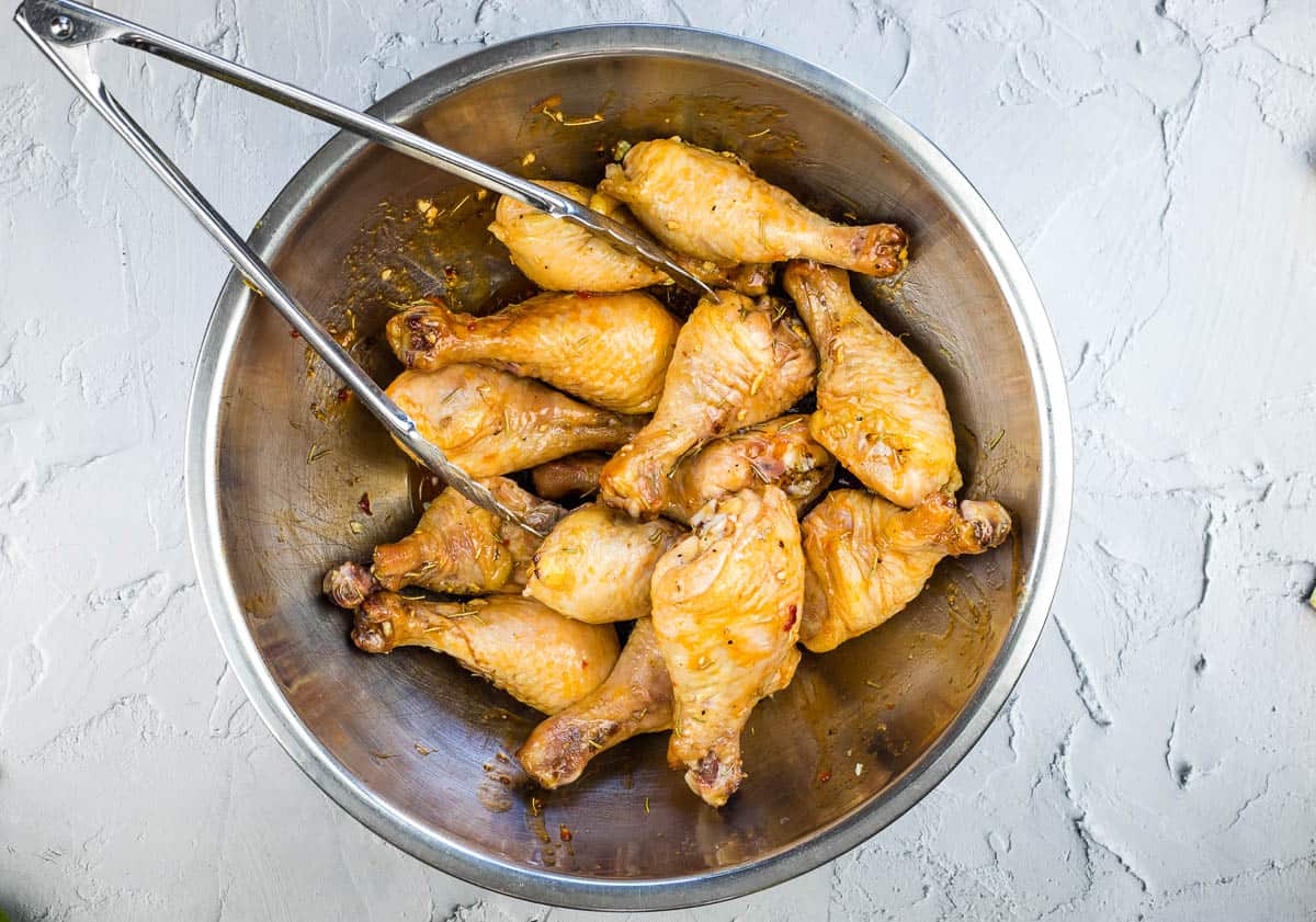 tossing chicken legs with the glaze in a large bowl