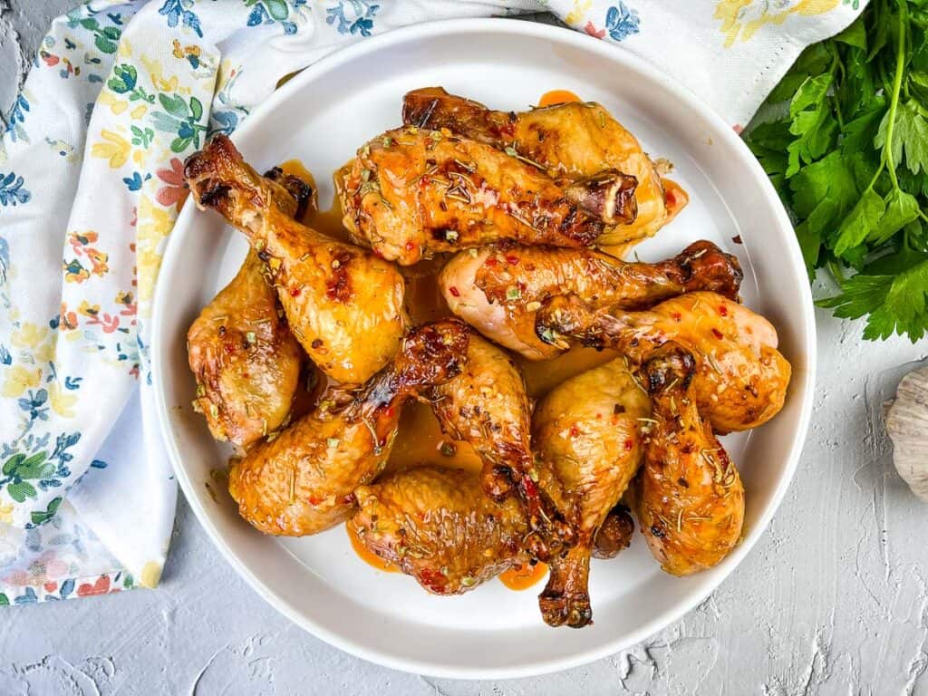 cooked smoked chicken legs with red pepper glaze on a white serving platter