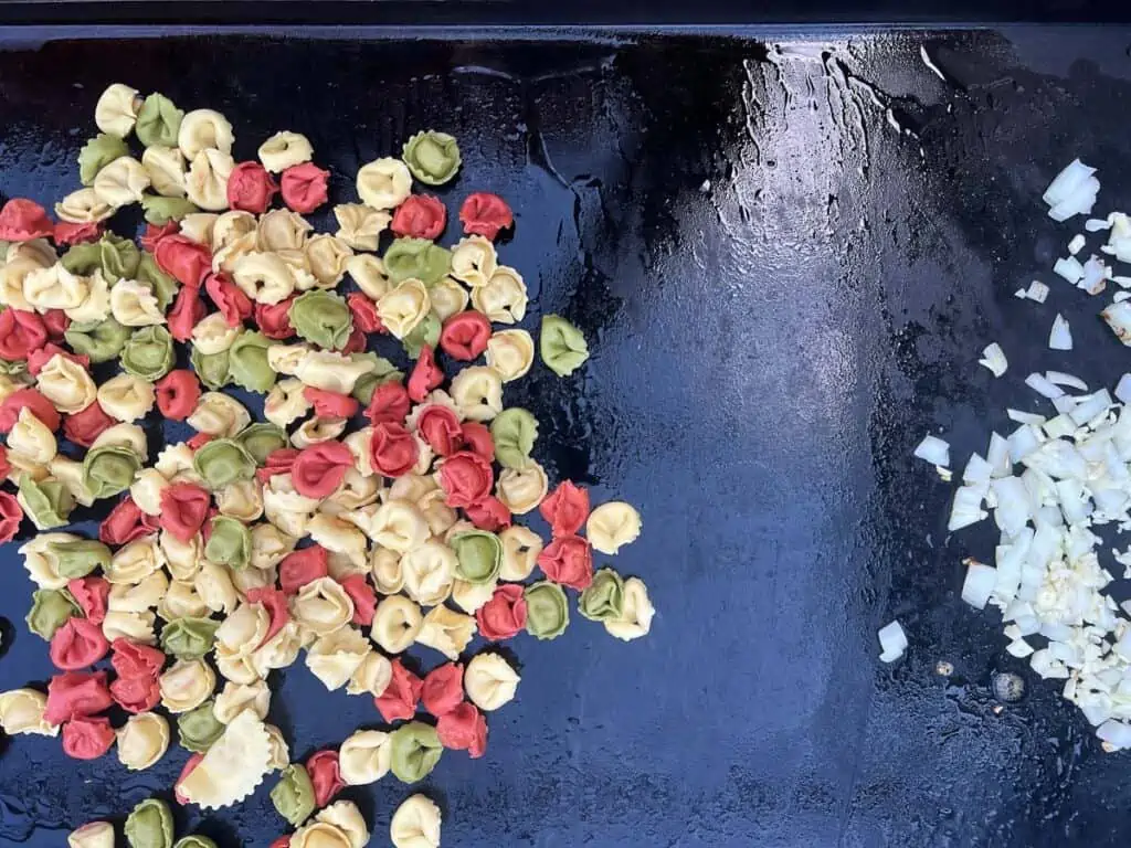tortellini cooking with onions sauteing next to it