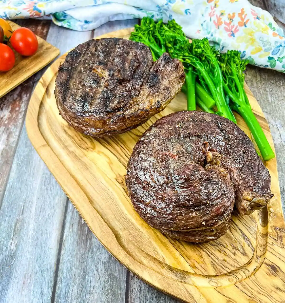 smoked ribeye cap steaks on a cutting board with broccolini
