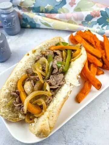 blackstone philly cheesesteaks on a plate with sweet potato fries