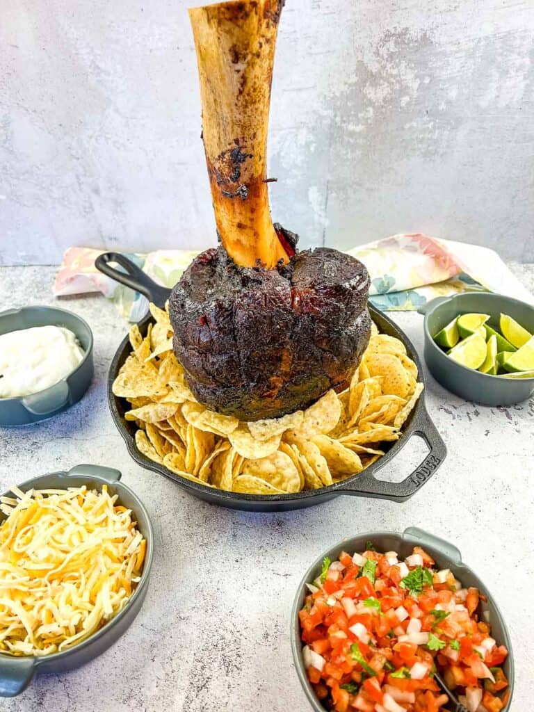 smoked thor's hammer in a black skillet with nacho fixings around it
