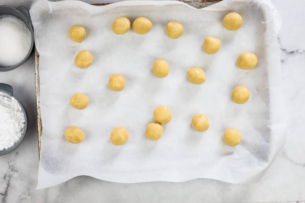 rolled balls of white chocolate crinkle cookie dough