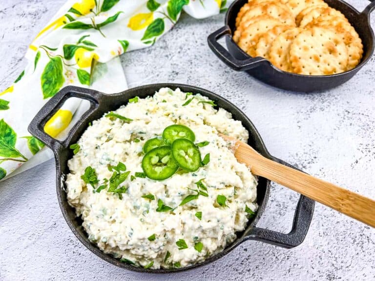 Artichoke-Jalapeno Dip in a round black bowl with crackers.
