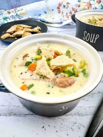 Turkey pot pie soup in a black soup bowl.